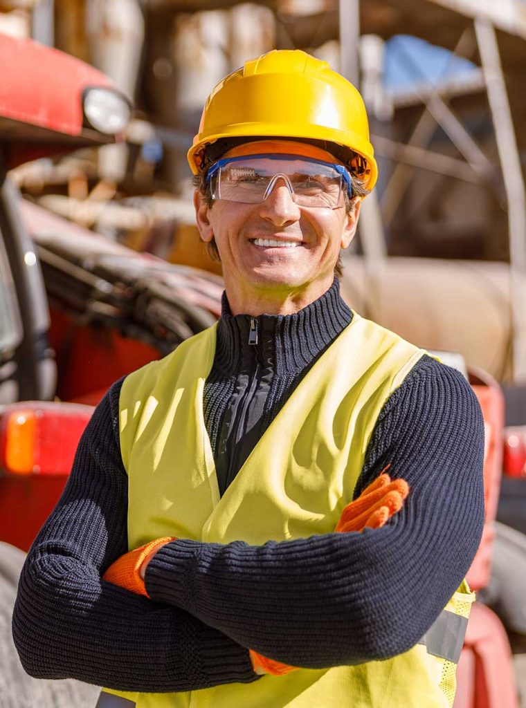 joyful-male-engineer-standing-by-tractor-at-factor-B54T3VP.jpg